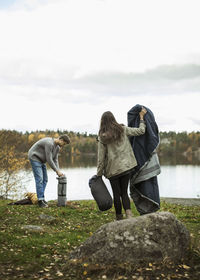 Young couple with blanket and sleeping bag at lakeshore