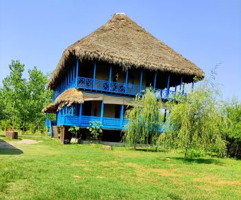 House on field against clear blue sky