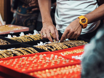 Midsection of people preparing food at market stall