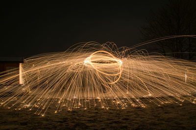 Light trails on beach against sky at night