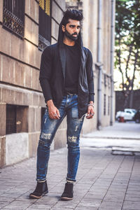 Thoughtful young man standing on footpath in city