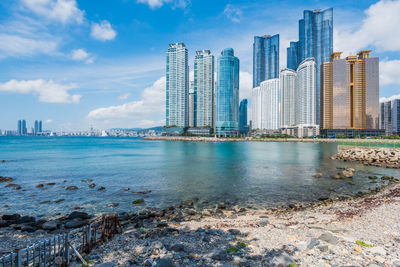 Sea by city buildings against sky