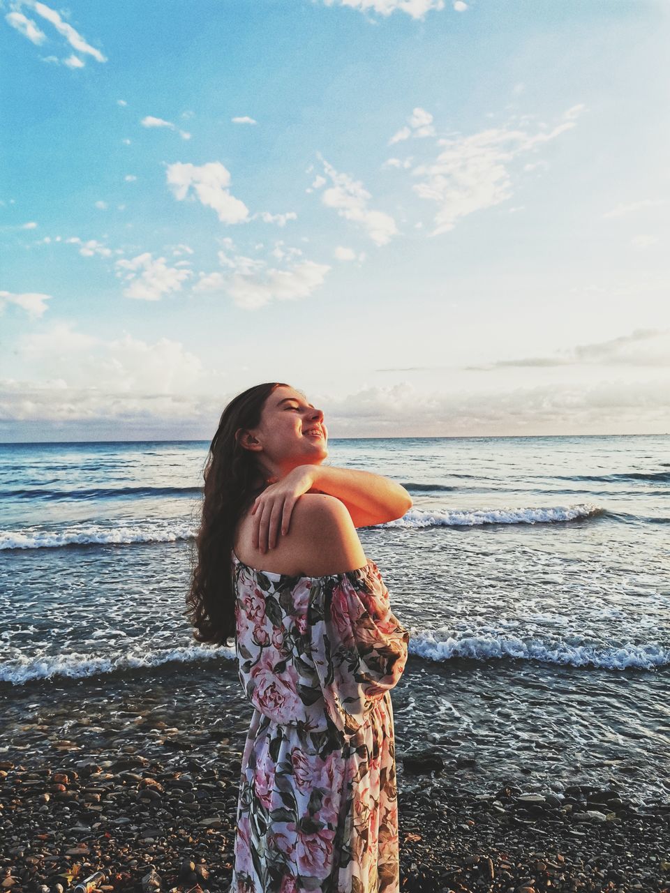 water, sky, sea, one person, beach, land, nature, women, adult, young adult, standing, horizon over water, holiday, dress, hairstyle, leisure activity, long hair, cloud, beauty in nature, vacation, trip, clothing, horizon, smiling, blue, tranquility, happiness, sunlight, ocean, female, emotion, casual clothing, looking, day, relaxation, shore, outdoors, photo shoot, fashion, lifestyles, three quarter length, travel, summer, scenics - nature, brown hair, side view, person, sunset, travel destinations, looking away, carefree, enjoyment, coast, tranquil scene, contemplation, full length, idyllic, positive emotion, portrait, copy space