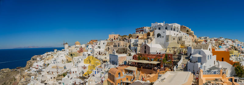Panoramic view of buildings by sea against blue sky