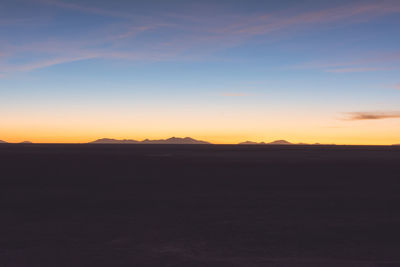 Dark landscape against scenic sky at sunset