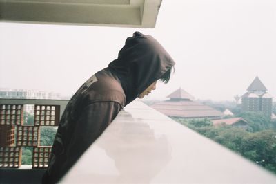 Man by glass building against clear sky