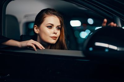 Young woman looking at side-view mirror of car