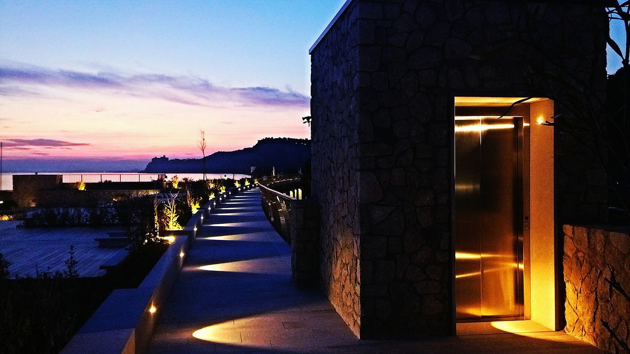 architecture, built structure, sky, building exterior, sunset, illuminated, the way forward, street, road, dusk, transportation, sunlight, cloud - sky, cloud, railing, outdoors, silhouette, shadow, no people, incidental people