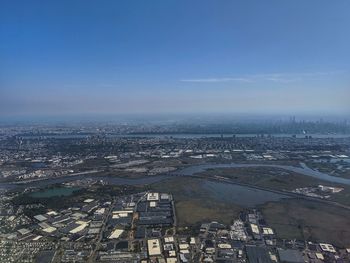 High angle view of city by river against blue sky