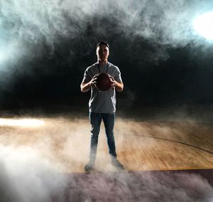 Full length of man holding basketball while standing in court