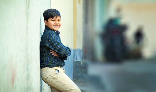 Side view of happy boy standing against wall