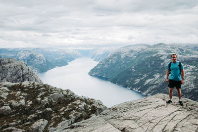 Rear view of man standing on mountain against sky