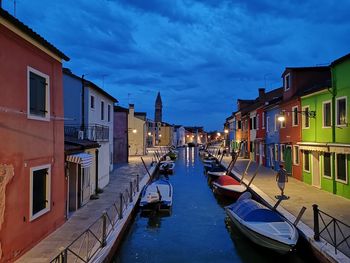 Boats moored in canal amidst buildings against sky