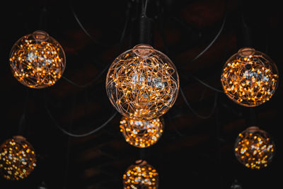 Low angle view of illuminated pendant lights hanging from ceiling