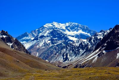 Scenic view of snowcapped mountains against clear blue sky