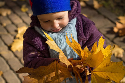 Smiling cute girl holding dry leaves during autumn
