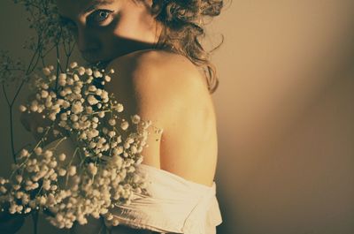 Portrait of sensual woman with flowers against wall