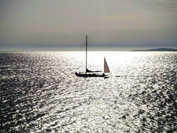 Silhouette sailboat sailing on sea against sky during sunset