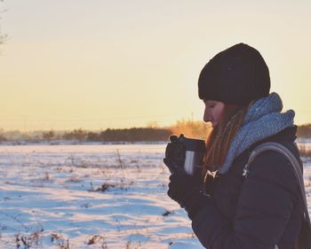 Woman on snow field against clear sky during sunset