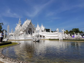 View of river by temple against sky