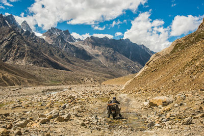 Man riding motorcycle on mountain against sky