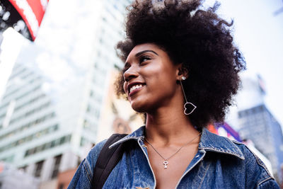 Low angle view of happy young woman with afro hairstyle in city