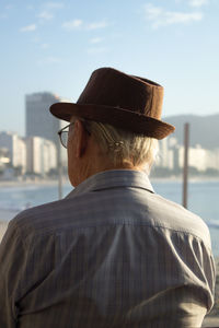 Side view of man wearing hat looking at sea against sky