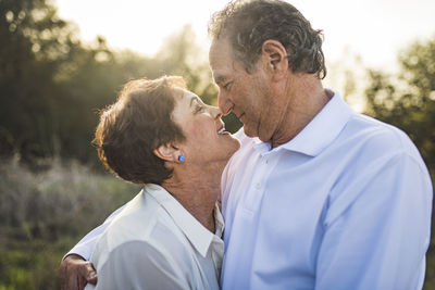 Senior couple hugging and looking at each other outside in backlight