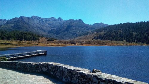 Scenic view of lake and mountains against clear blue sky