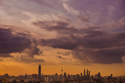 Buildings in city against cloudy sky during sunset