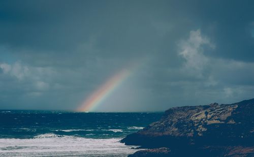 Scenic view of rainbow over sea against sky