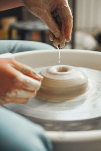 Beautiful female hands create a clay product on pottery wheel