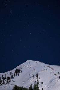 Low angle view of snow covered mountain against sky at night