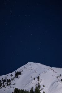 Low angle view of snow covered mountain against sky at night