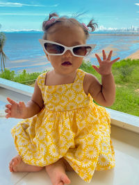 Portrait of cute baby girl with sunglasses against water