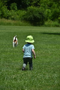 Rear view of girl with dog on field