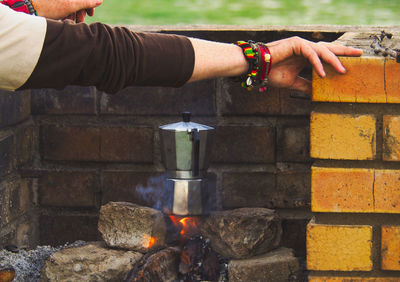 Cropped hands of person preparing food over fire