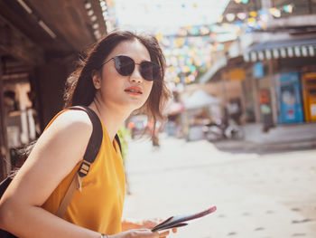 Portrait of young woman using mobile phone in city