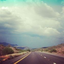 Country road against cloudy sky