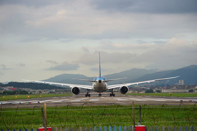 Airplane flying over runway against sky