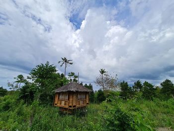 House on field by trees against sky