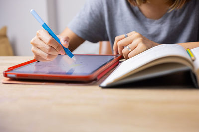 Midsection of man reading book on table