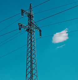 Low angle view of electricity pylon against clear blue sky