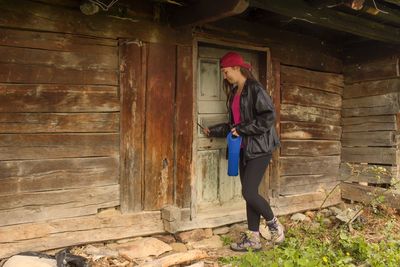 Full length of woman standing against wooden wall