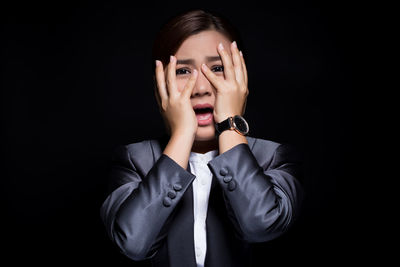 Portrait of scared businesswoman against black background