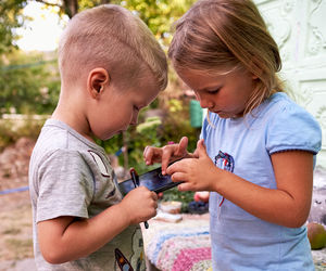 Side view of siblings using smart phone