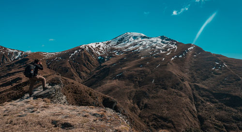 Man photographing on mountain against blue sky