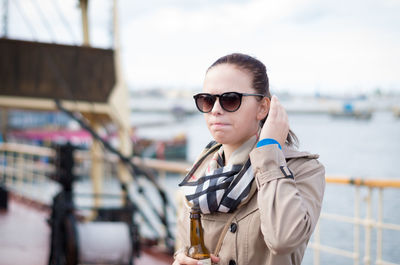 Girl with sunglasses and scarf holding bottle