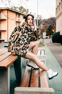 Young woman using phone while sitting on bench