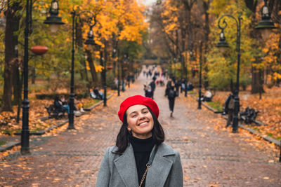 Portrait of young woman standing against trees